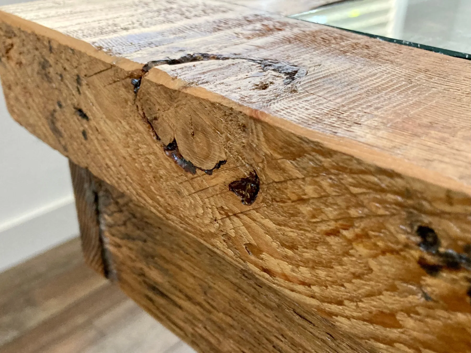 Close-up of the Passato frame edge: reclaimed timber with an open knot, the glass edge just visible.